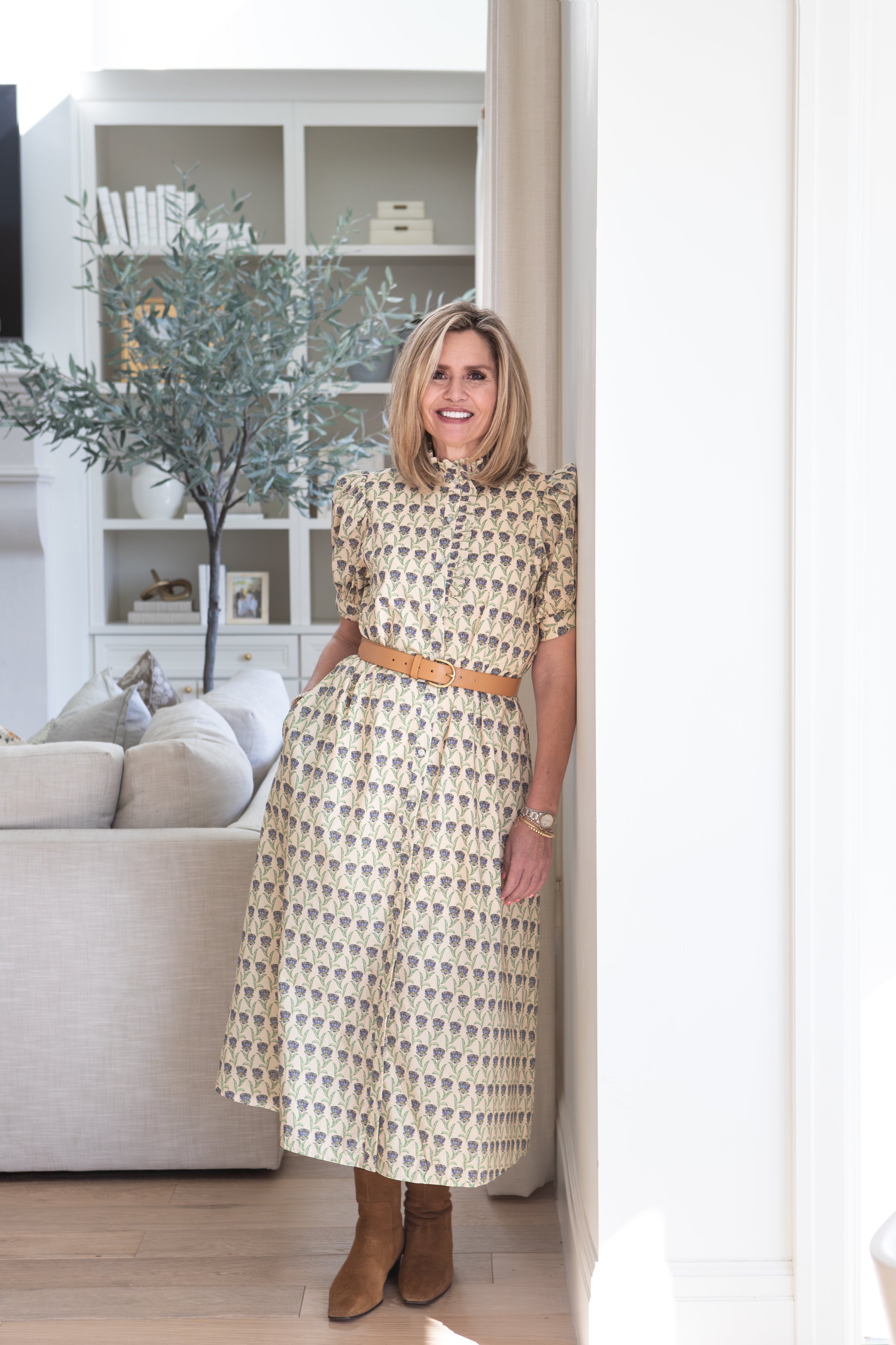 Woman in a patterned dress standing in a living room.